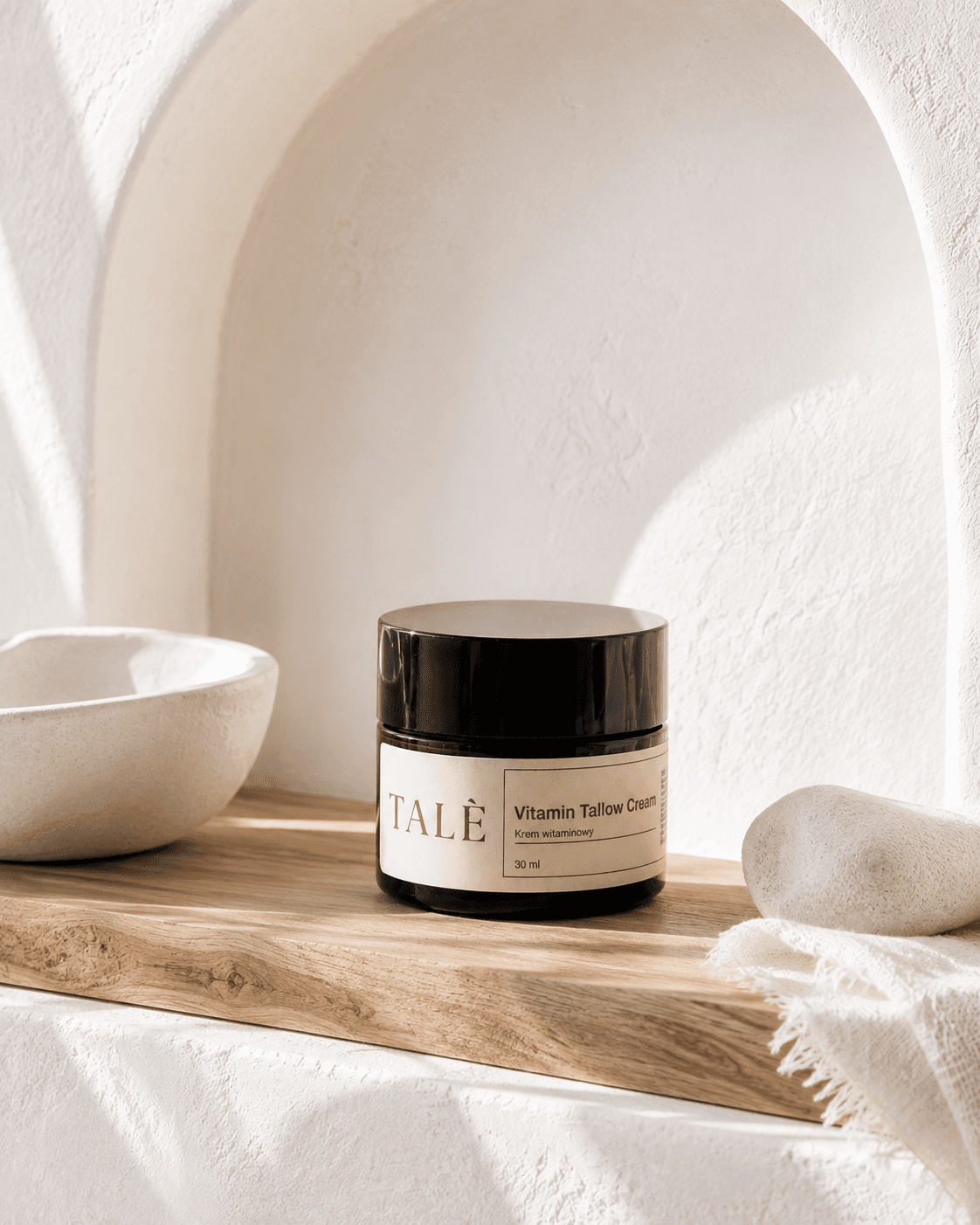 Słoik kremu Vitamin Tallow Cream na drewnianej półce obok ceramicznej miski