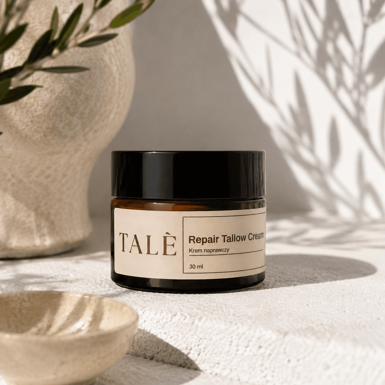 Słoik kremu Repair Tallow Cream na kamiennej półce wśród gałązek oliwnych