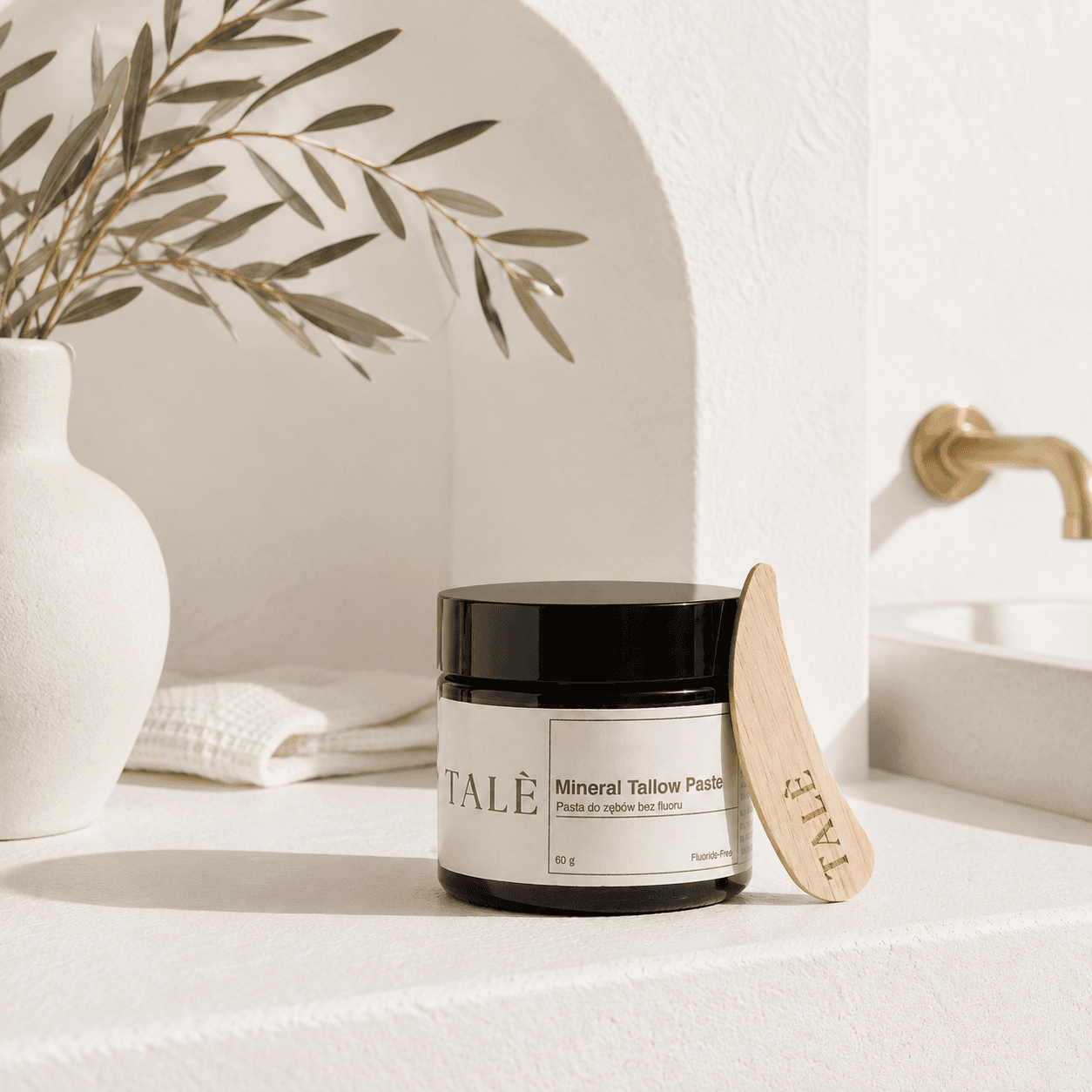 Słoik pasty Mineral Tallow Paste z drewnianą szpatułką w jasnej łazience