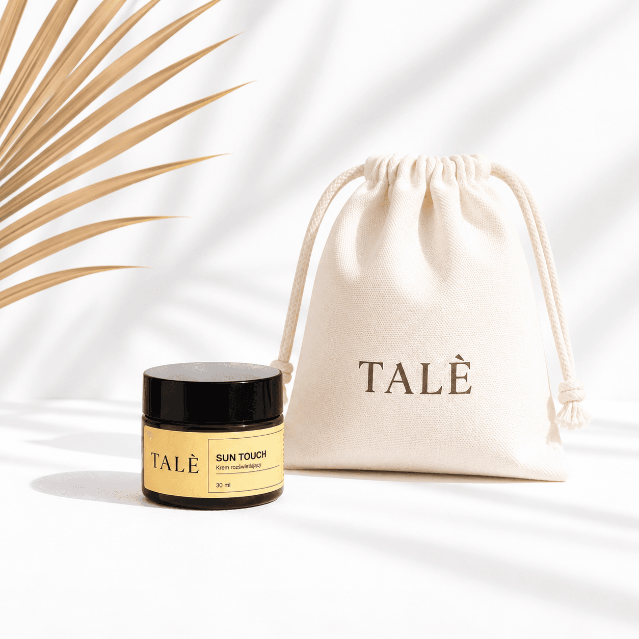 Jar of TALÈ Sun Touch beside a cotton pouch with the TALÈ logo