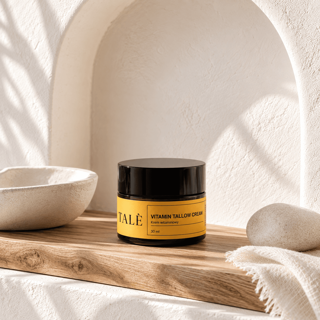 Słoik kremu TALÈ Vitamin Tallow Cream na drewnianej półce obok ceramicznej misy i kamienia
