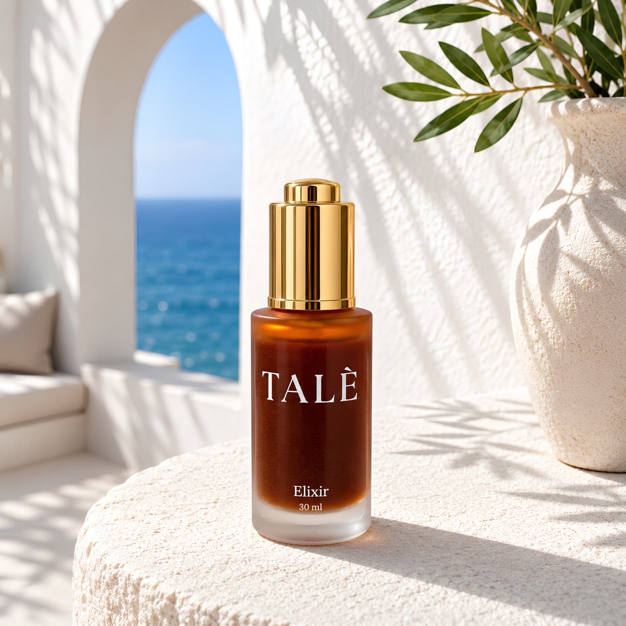 Butelka serum TALÈ Elixir na kamiennym blacie, w tle łukowe przejście z widokiem na morze