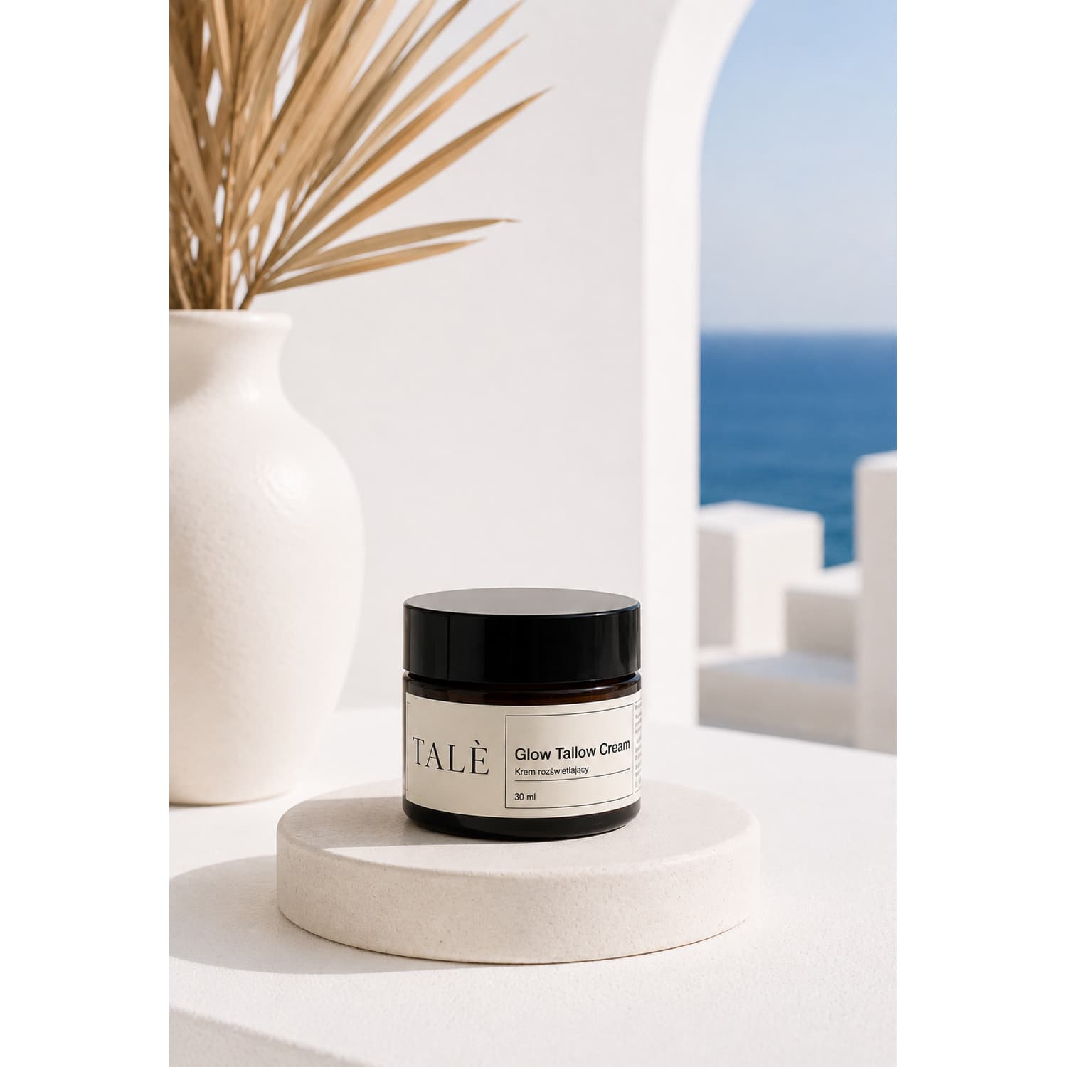 Słoik kremu Glow Tallow Cream na kamiennym podeście, w tle wazon i morze
