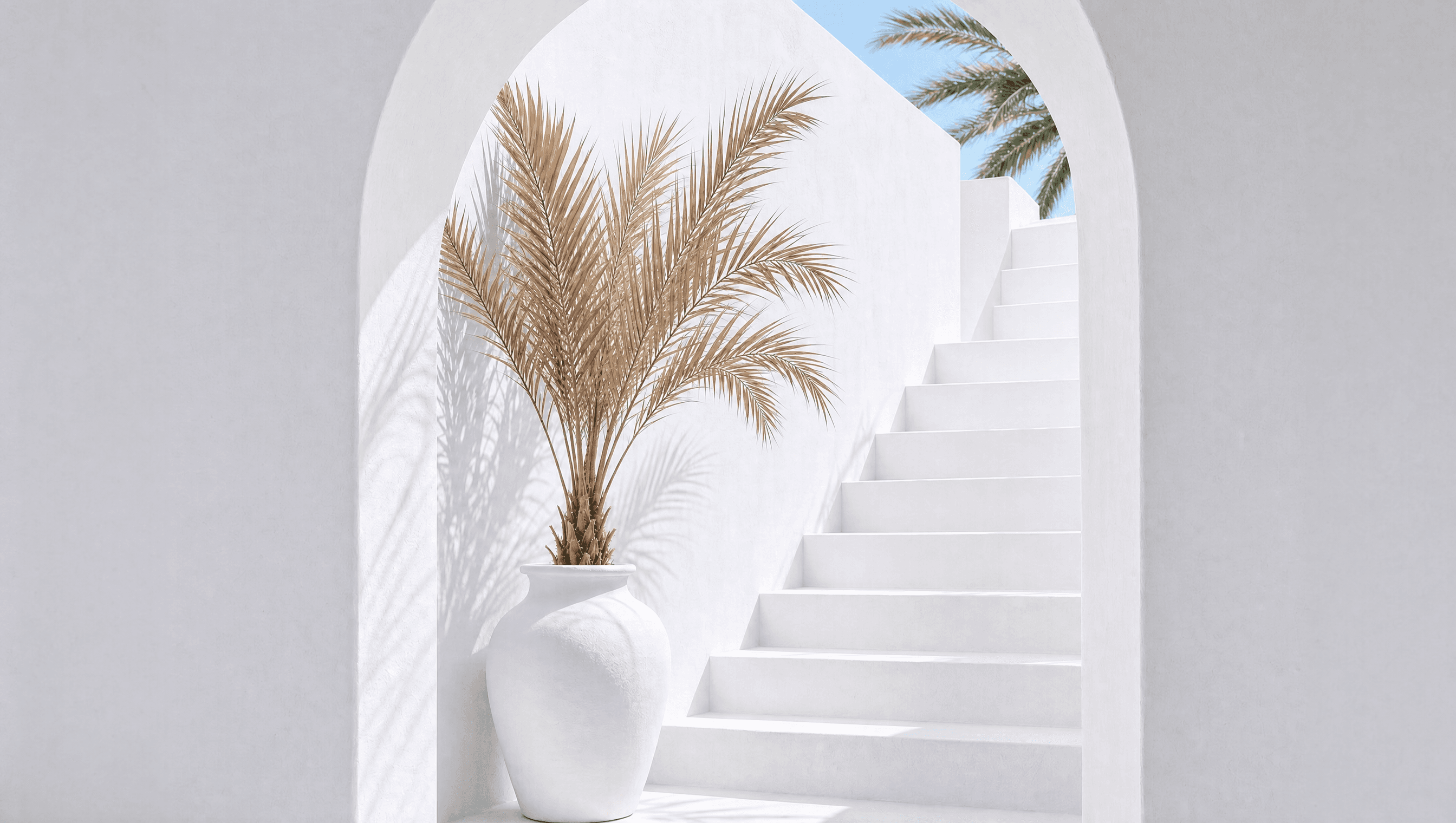 Beige arch with stairs and a vase holding dried palm leaves