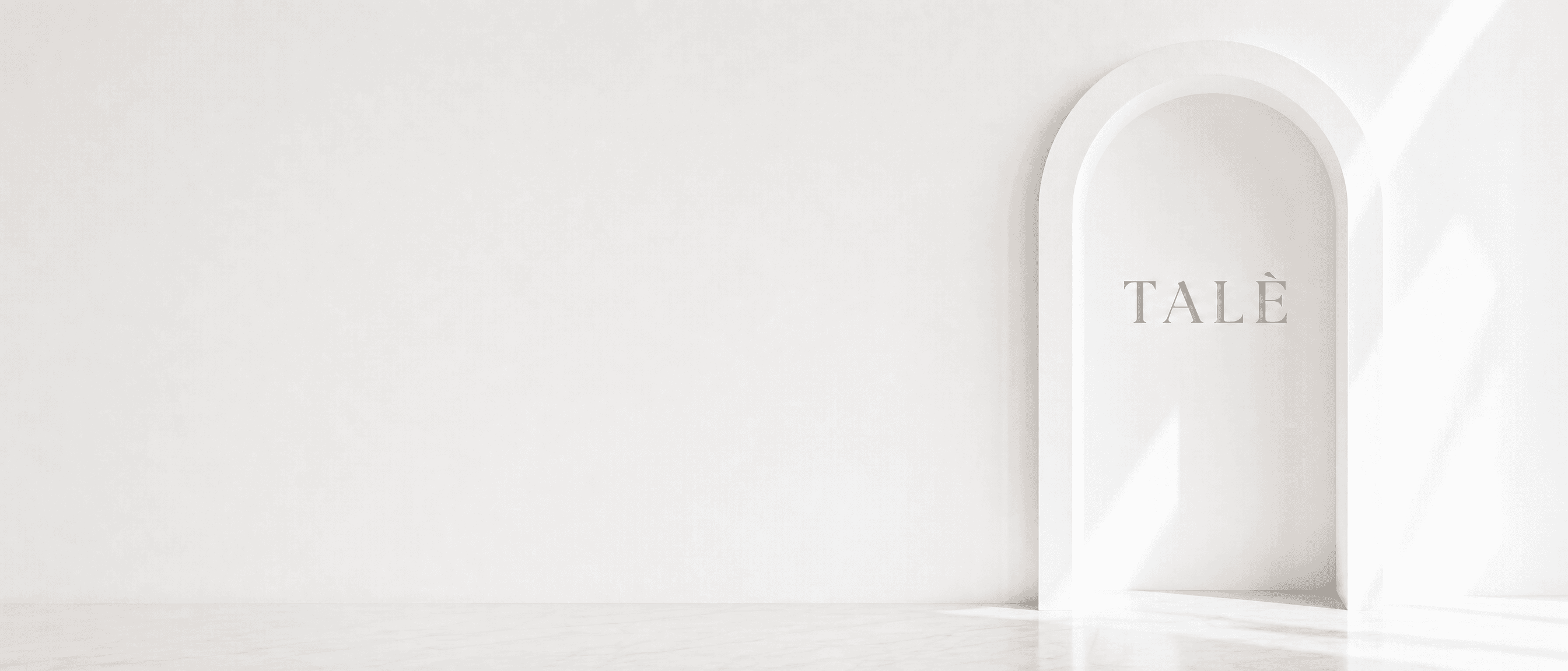 White wall with an arched niche engraved with the TALÈ wordmark, and a marble floor